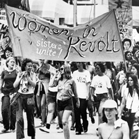 Women Marching with a sign that says Women in Revolt.